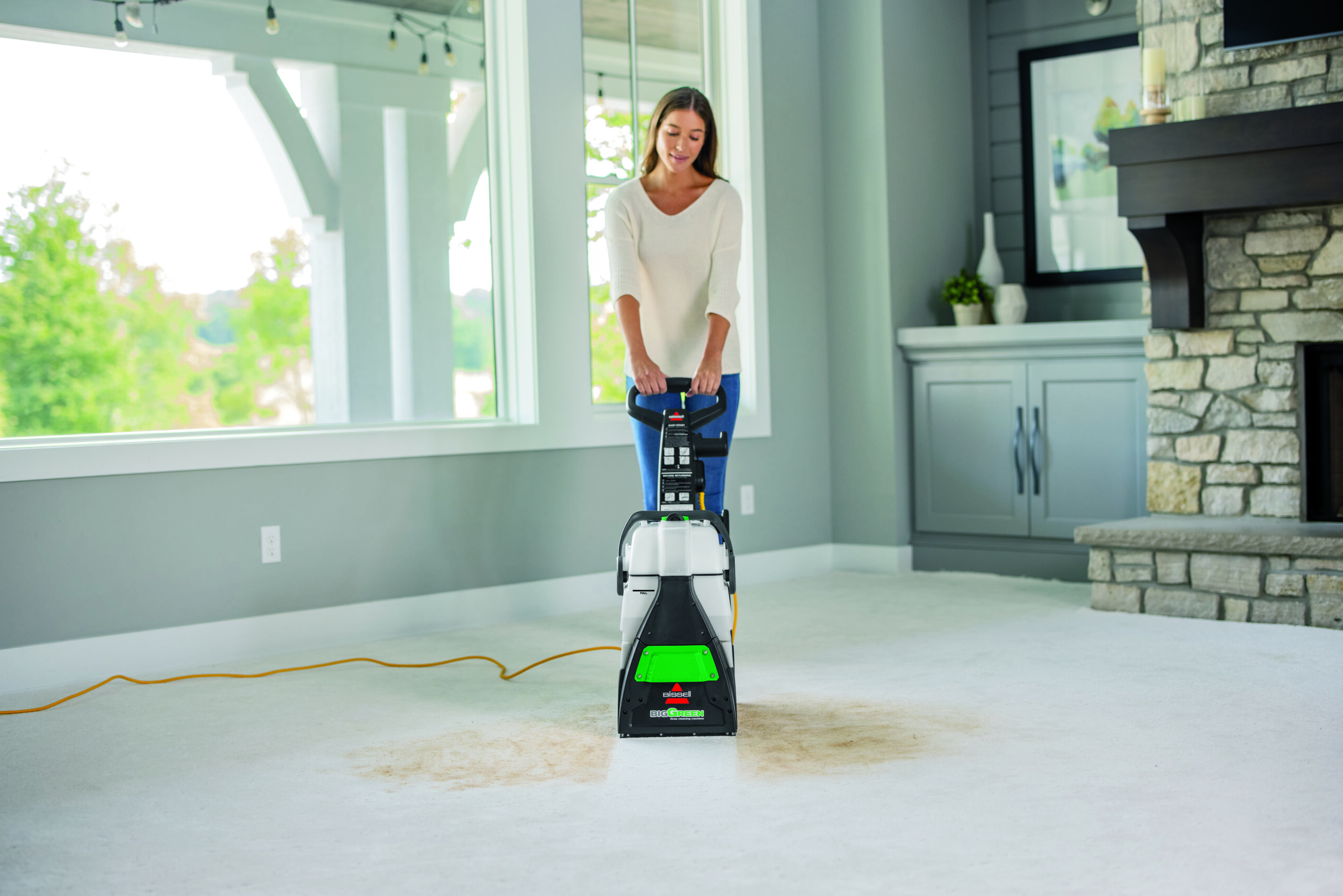 Woman cleaning carpet with a BISSELL Big Green machine